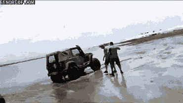jeep stuck in beach sand gets a tow rope